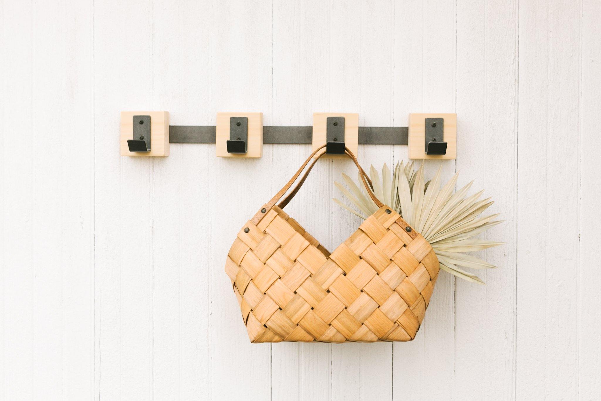 wood hook rack with metal hooks and bar holding a small wood basket