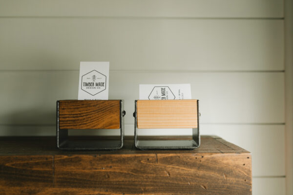 two small wooden business card holders. one is stained in dark walnut and one features a natural stain