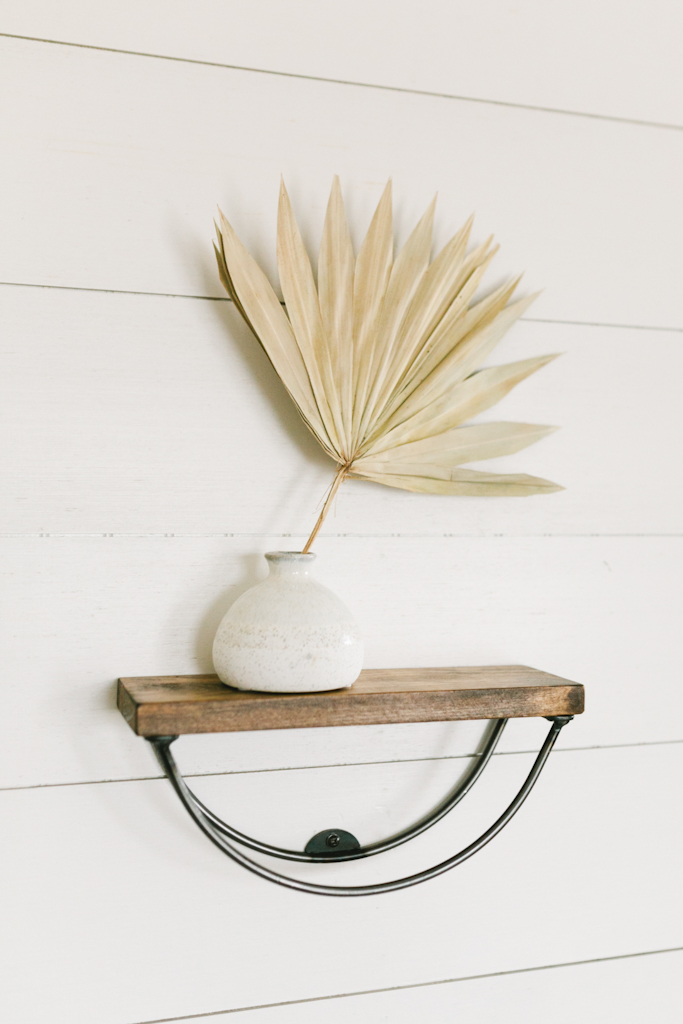 minimalistic wooden arch shelf holding a decorative piece