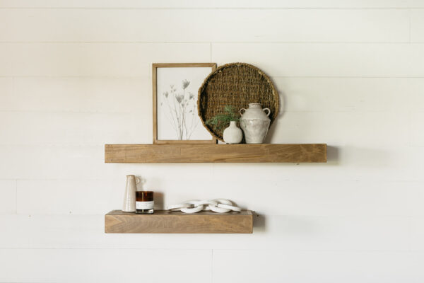 medium and large floating wooden shelves hanging on a wall holding small houseware items