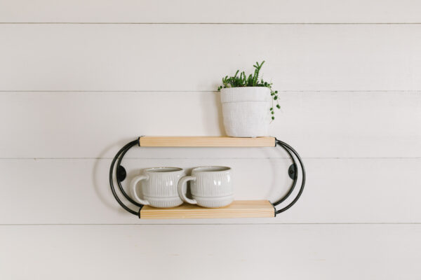 wooden oval shelf holding two coffee mugs and a small planter