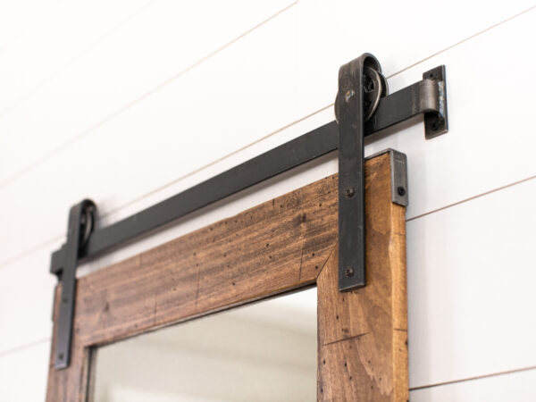 closeup of a wooden framed mirror and metal wall track hung vertically