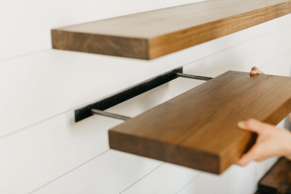 sliding the deep floating wooden shelf on the metal wall bracket